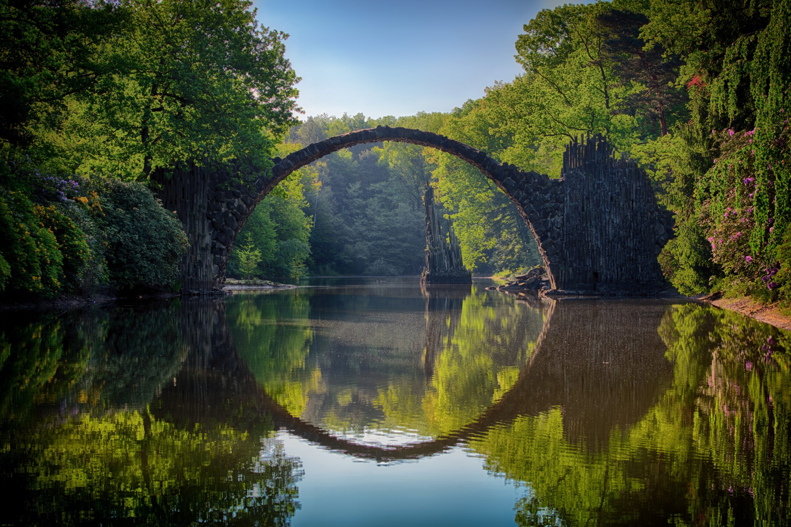 A circular bridge over water, surrounded by trees.